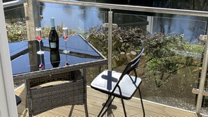 Varanda com mesa e cadeiras de vidro com vista para um corpo de água.