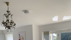 Uma sala de estar com dois sofás de couro, um candelabro, um quadro, um vaso de planta e uma porta de vidro deslizante para uma varanda.