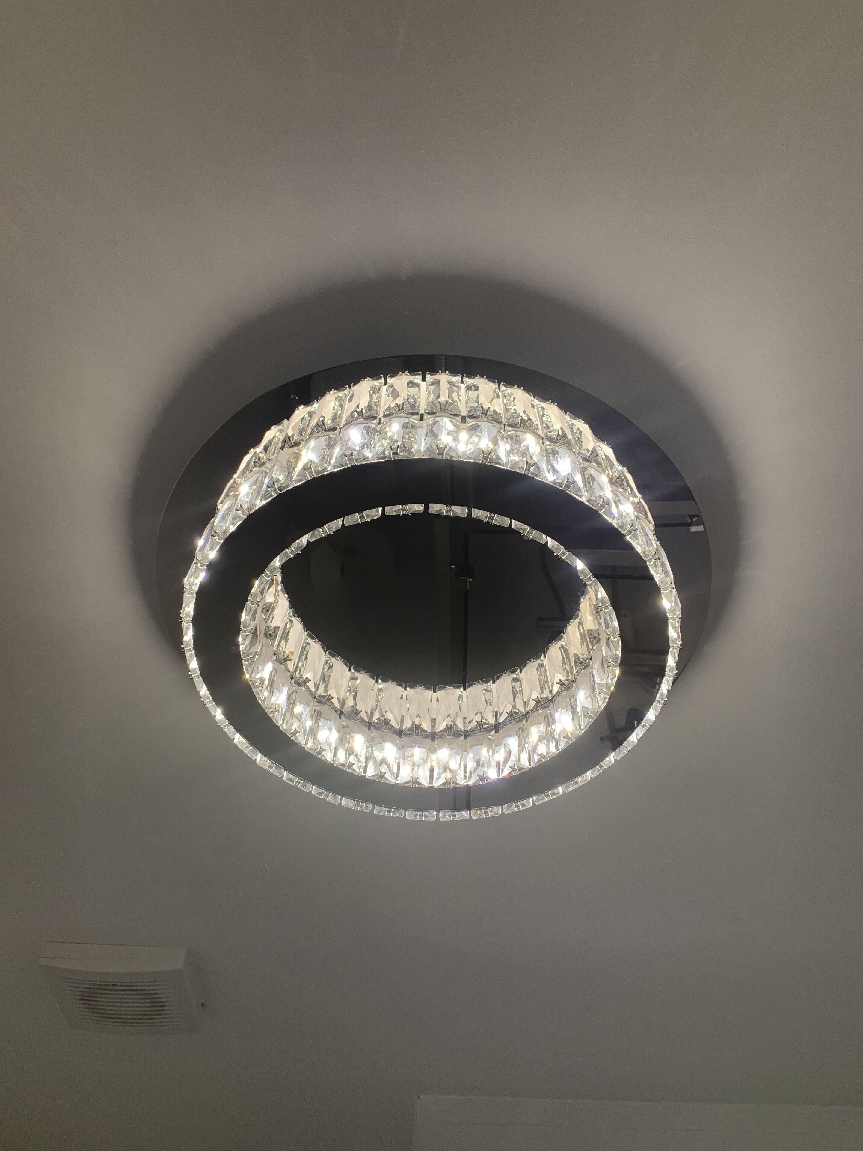 Een ronde kroonluchter met meerdere lagen kristal.