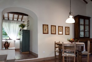 A dining area with a table and chairs, a hanging light fixture, and framed botanical prints on the wall. - Entire home hosted by Agriturismo Castello Di Montozzi (Pergine Valdarno)