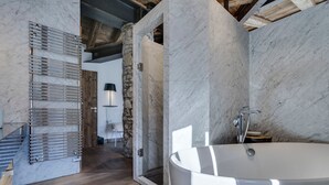Une salle de bain moderne avec une grande baignoire, un plancher en bois et un mur en pierre.