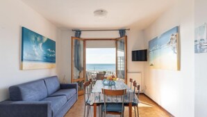 Una habitación con una mesa de comedor, sillas, un sofá y vista al mar.