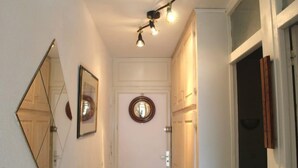 A hallway with a white door, a round mirror, and a ceiling light fixture. - Castel des Roches C4 by Interhome (Saint Gervais)