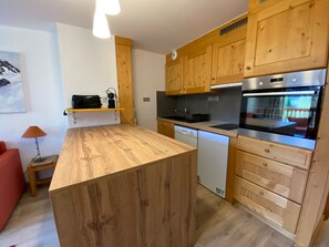 A modern kitchen with wooden cabinets, a built-in oven, and a dishwasher.