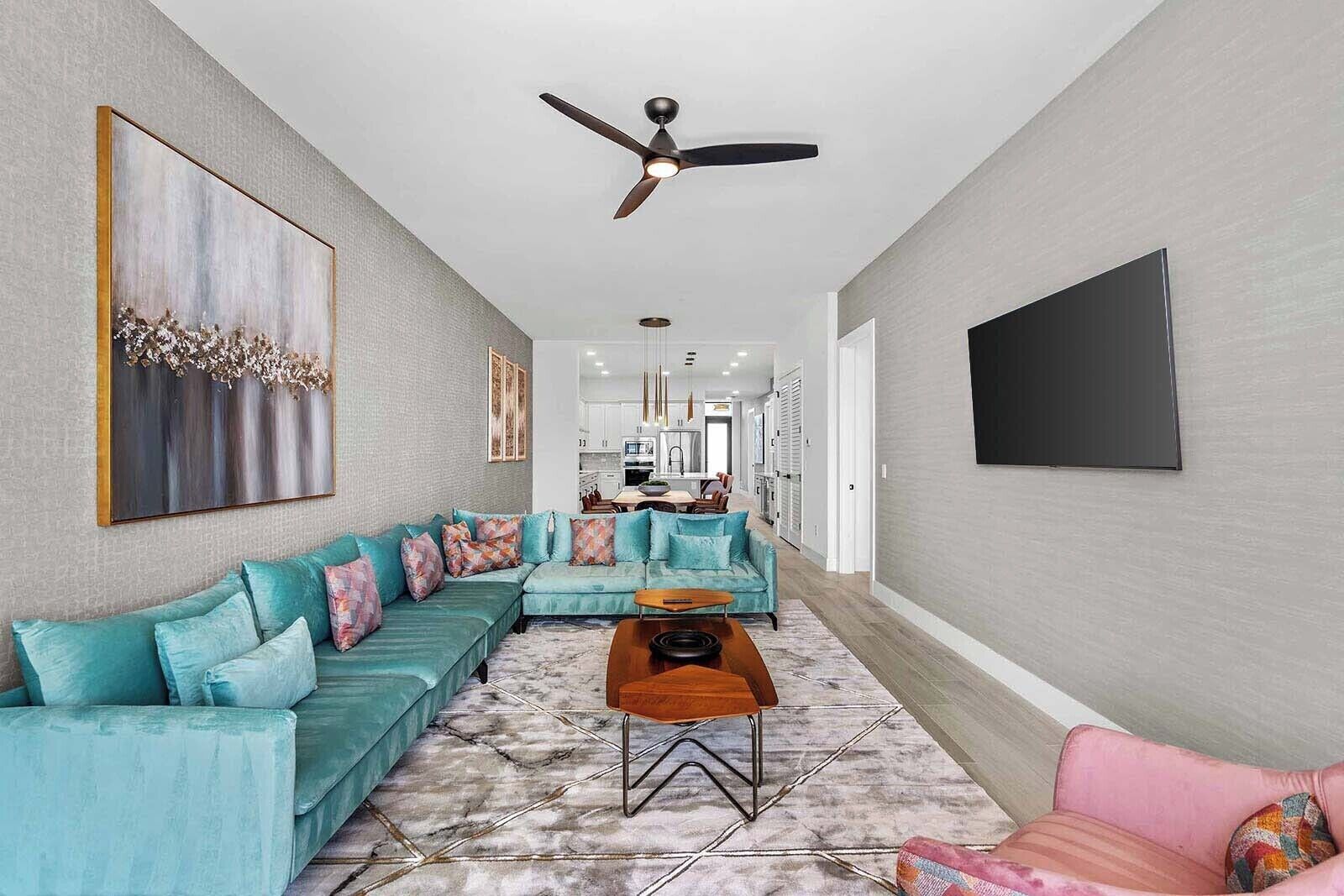A modern living room with a sectional sofa, a coffee table, and a ceiling fan.
