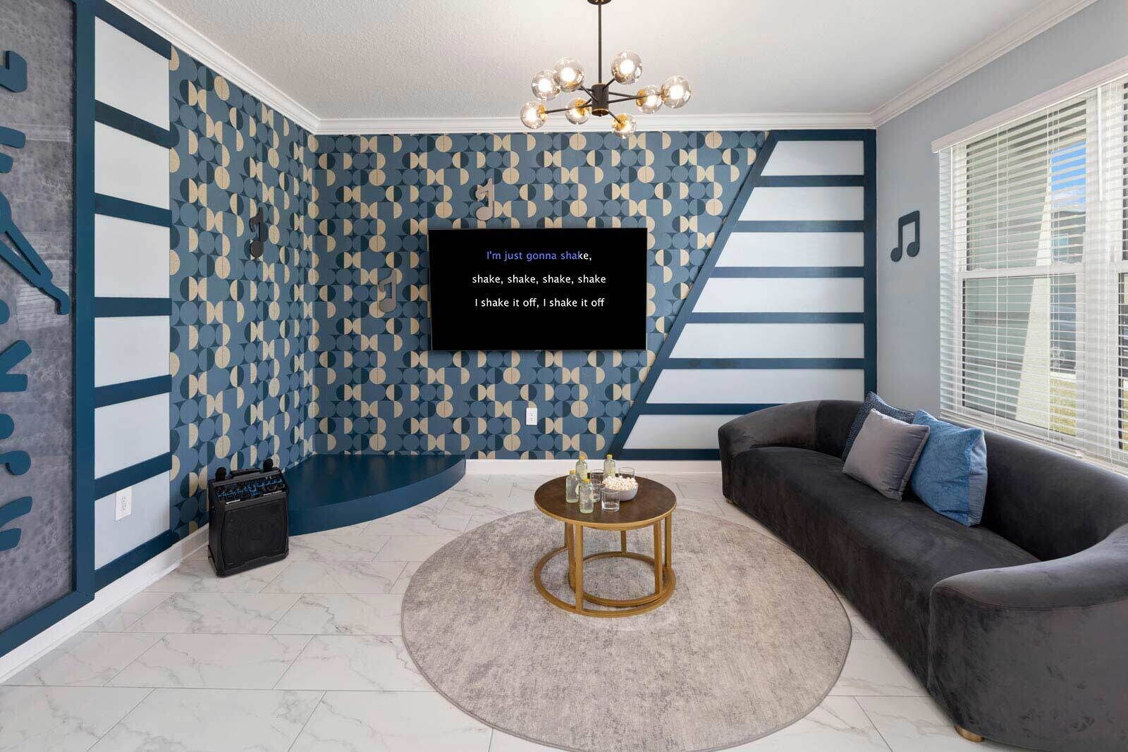 Un salon moderne avec un mur orné d’un motif, un canapé foncé, une table basse ronde et un lustre.