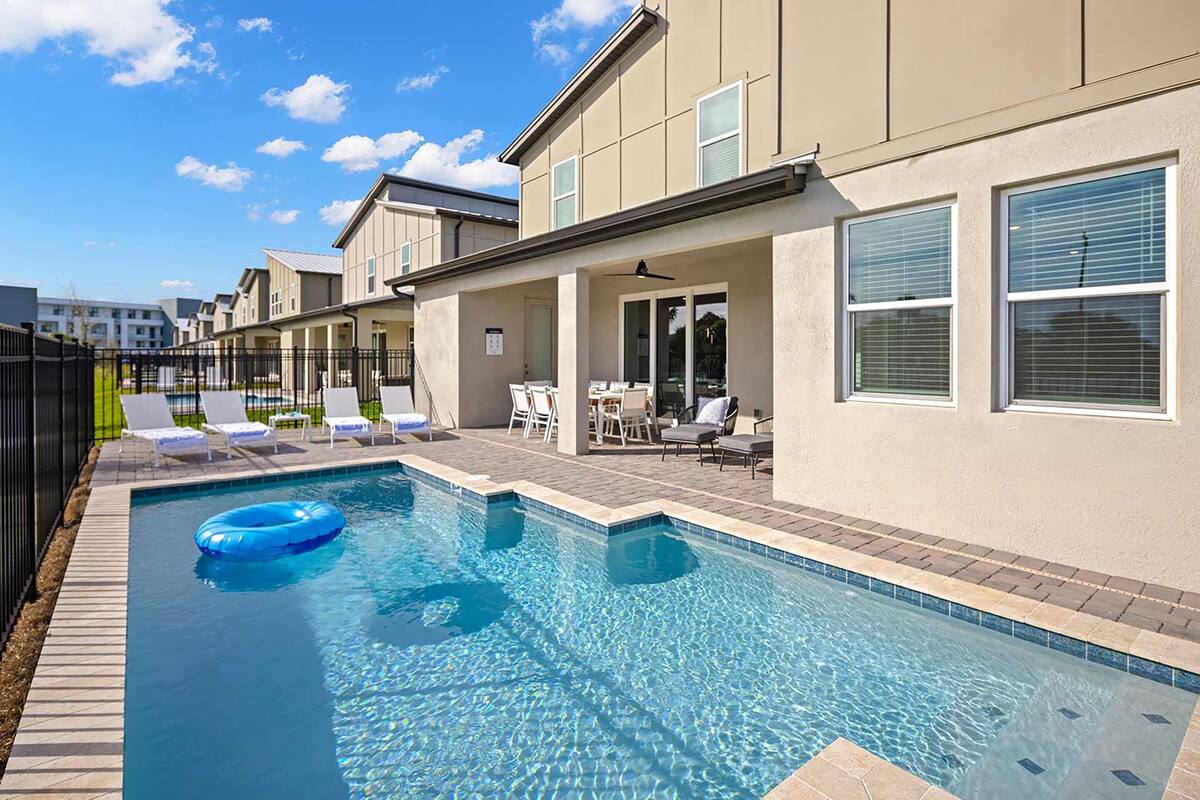 Ein Swimmingpool mit Liegestühlen und einer überdachten Terrasse.