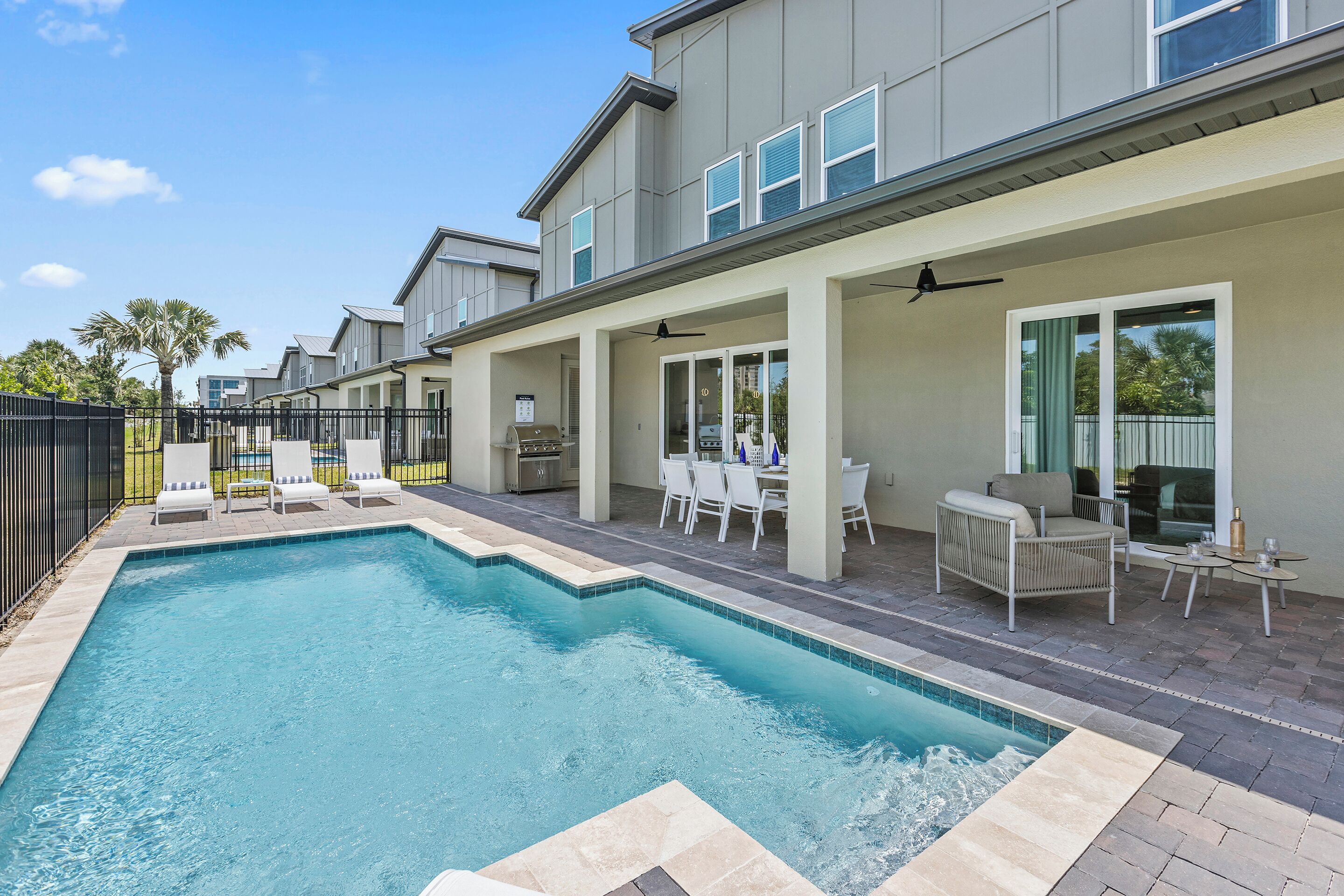 Une piscine avec des chaises longues et un espace patio aménagé avec du mobilier d’extérieur.