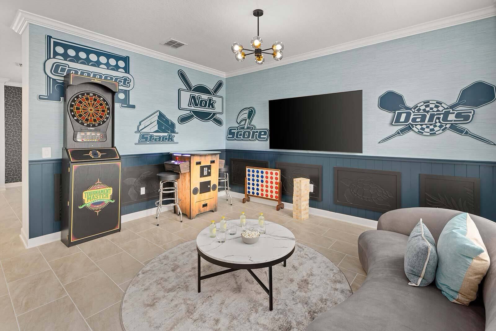 Una habitación con dardos, máquina de dardos, mesa de billar y televisión.