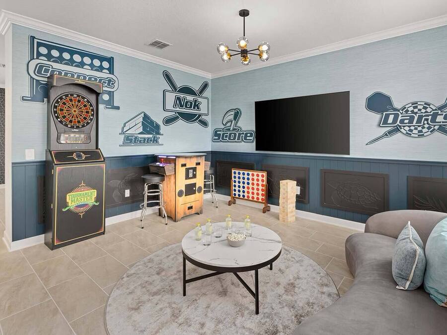 Una habitación con dardos, máquina de dardos, mesa de billar y televisión.
