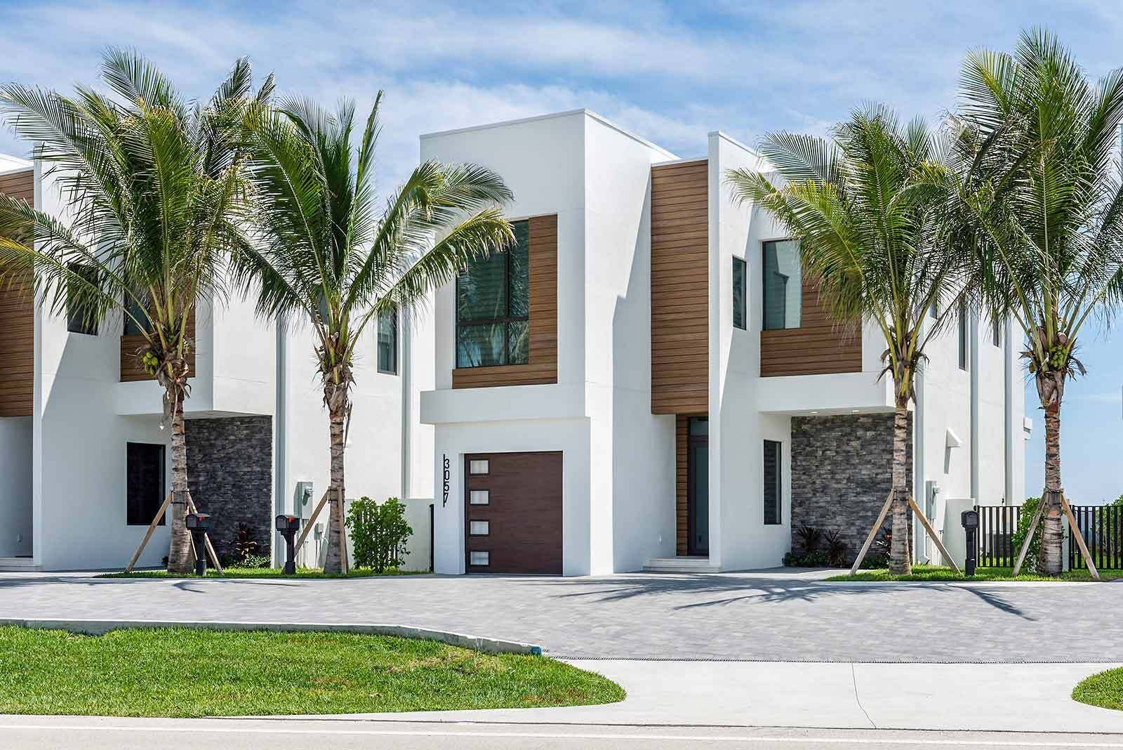 Ein modernes, zweistöckiges Haus mit weißer Fassade, großen Fenstern und einer Garage.
