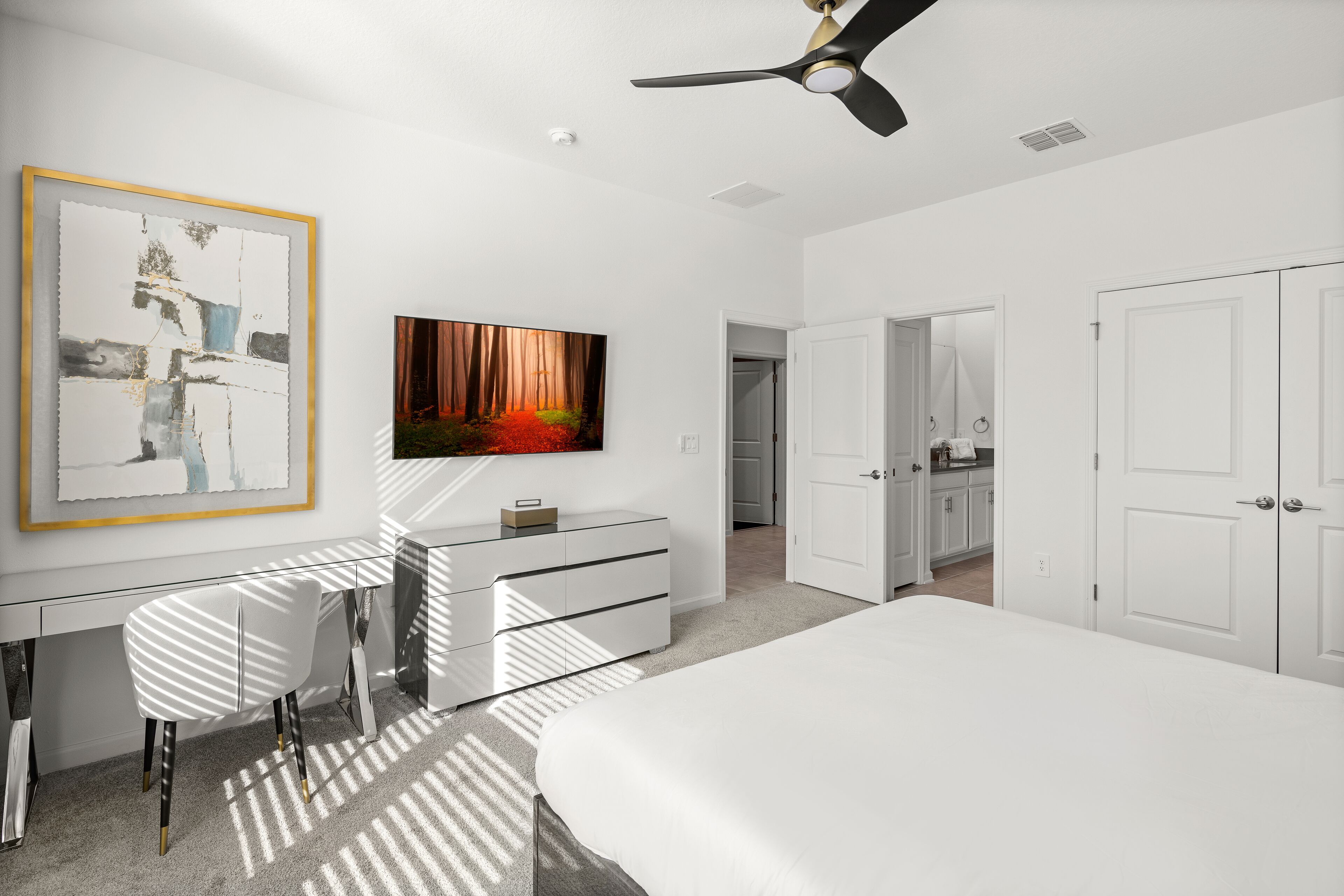 Une chambre à coucher moderne avec un lit, un bureau et un téléviseur.