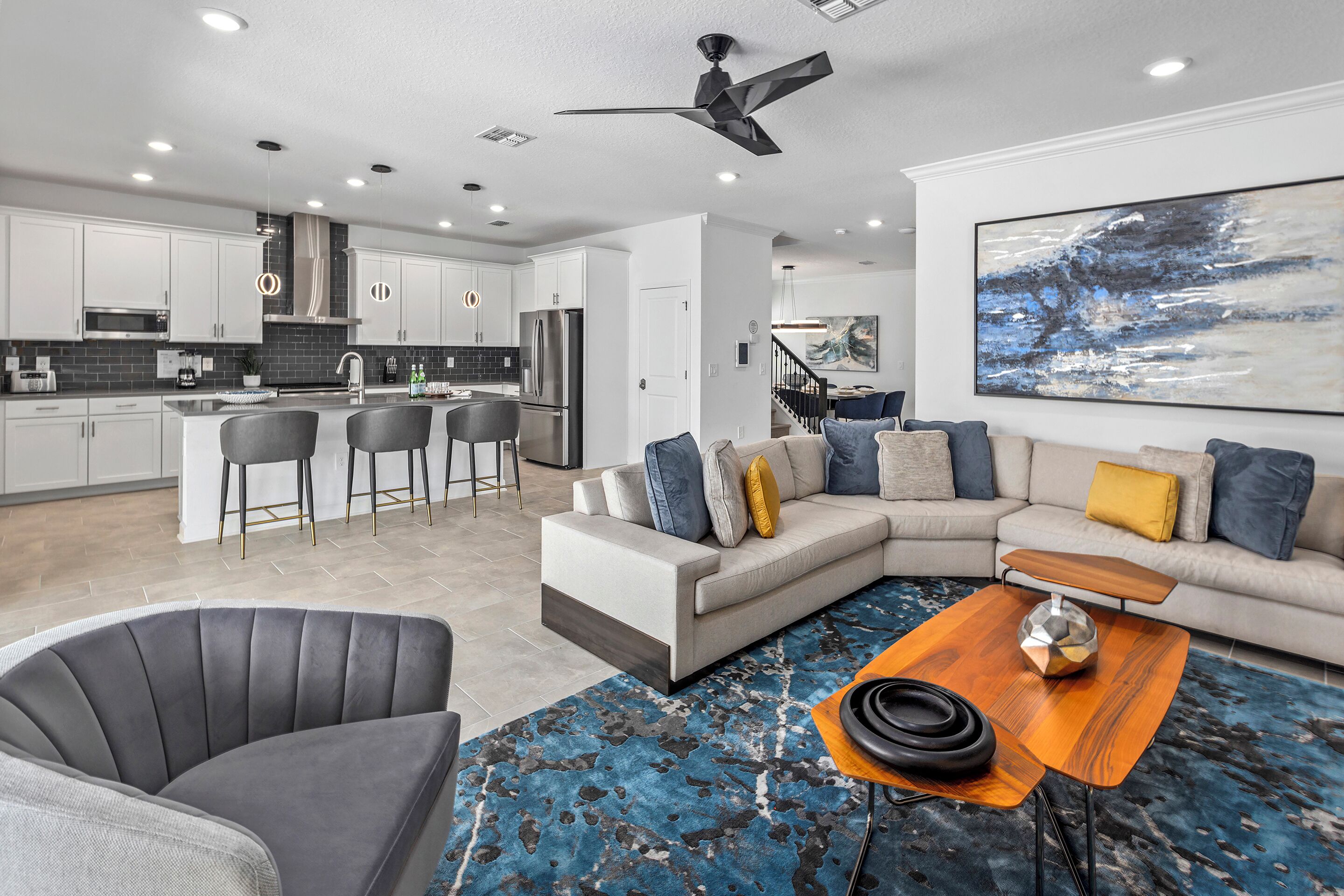 A modern kitchen with white cabinets, a central island, and a dining area with bar stools.