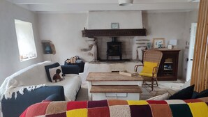Un salon chaleureux avec une cheminée, un canapé, une table en bois et une couverture colorée.