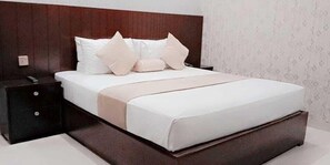 Un letto rifatto con cura, una testiera in legno, un comodino con cassetti e carta da parati decorata al muro.