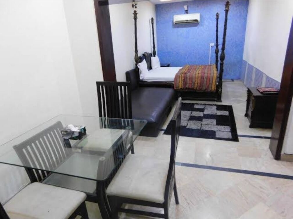 A room with a bed, a glass table, a sofa, and a small rug.