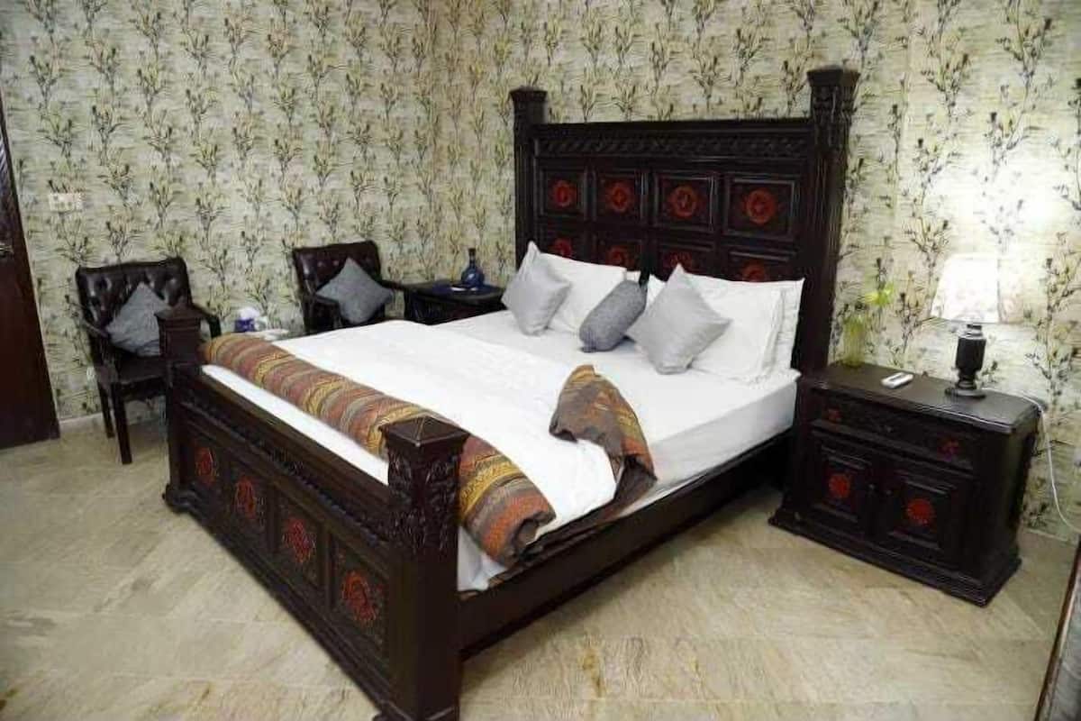 A traditional bed with a dark wooden headboard, two bedside tables, and a chair.