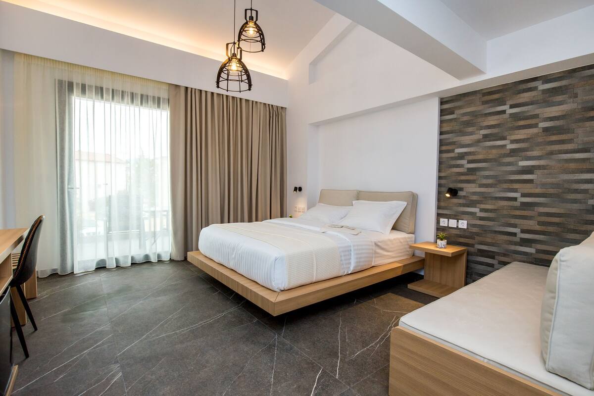 A modern bedroom with a large bed, a wooden bedside table, a small bedside lamp, and a built-in wall unit.