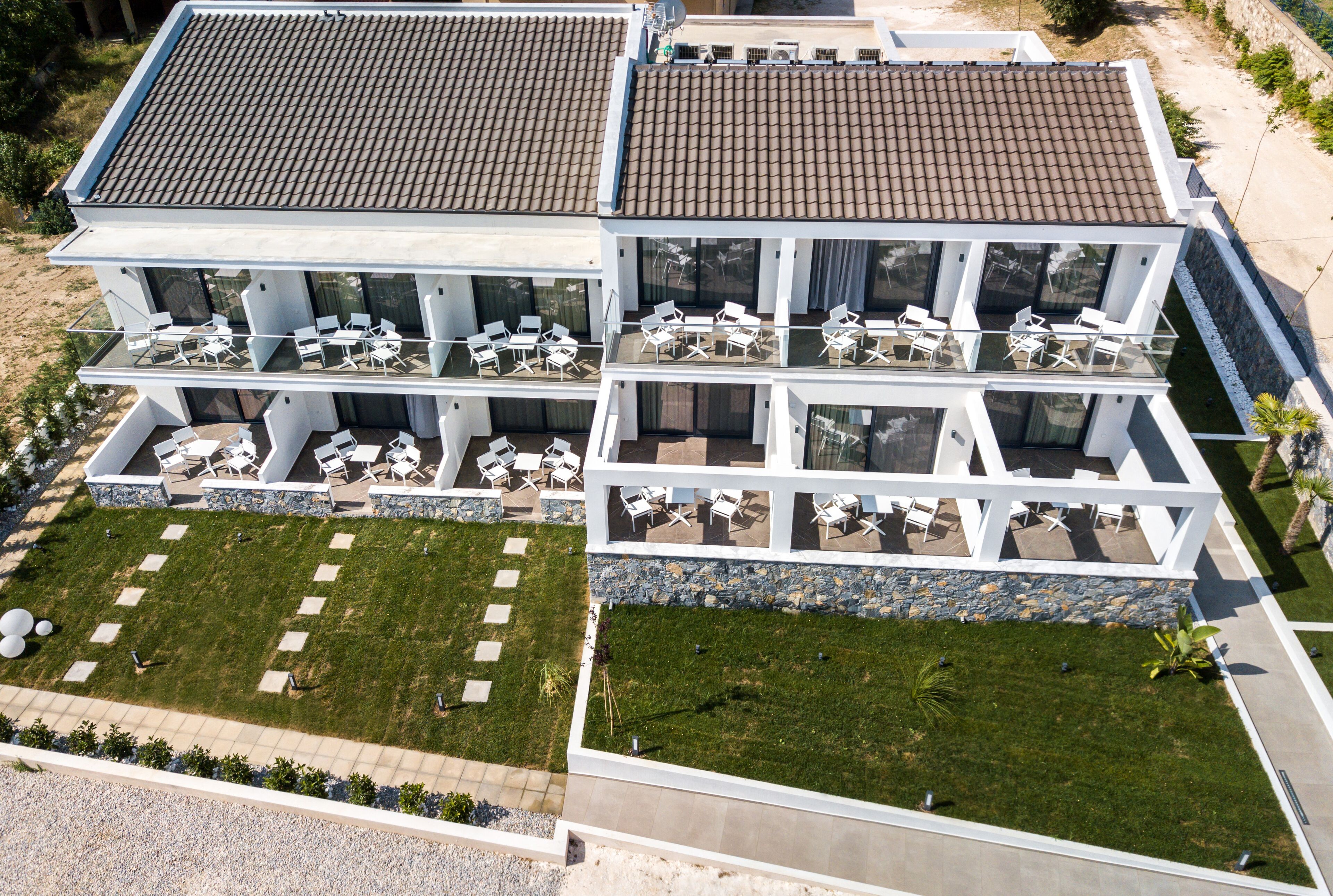 A modern hotel with multiple balconies, outdoor seating areas, and a well-maintained lawn.