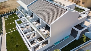 Un hotel moderno con diversi balconi, zone relax all'aperto e una piscina.
