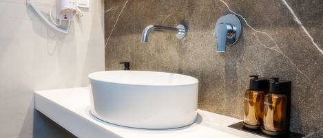 A bathroom with a white sink, a modern faucet, and two bottles of hair and body care products on the counter.