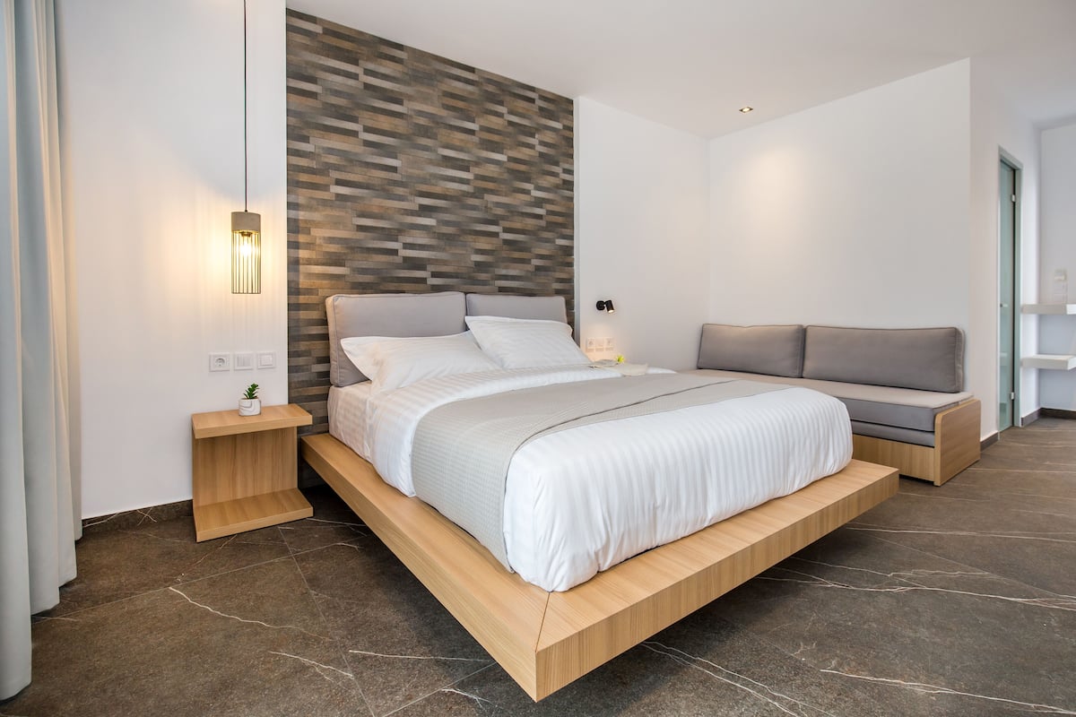 A modern bedroom with a bed, bedside tables, a wall-mounted light, and a built-in bench.