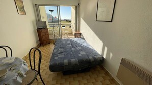 A small, compact room with a bed, a table with chairs, a dresser, and a TV.