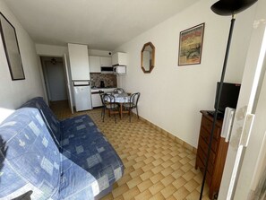 A compact living space with a kitchenette, a dining area, and a sofa.