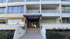 A multi-story building with a central entrance, balconies, and a covered walkway.