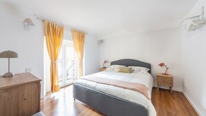 A bedroom with a bed, bedside tables, a lamp, curtains, and a wooden dresser.