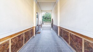 A hallway with a marble floor, wooden paneling, and a gate leading to an outdoor area.