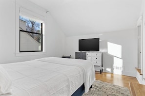 Una camera da letto con un letto, una televisione su un comò e una finestra con persiane.