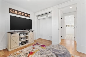 Un soggiorno moderno con televisione a schermo piatto, mobile porta TV in legno, tappeto colorato e una coperta accogliente.