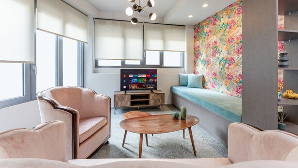 A modern living room with a sofa, armchairs, a coffee table, a flat-screen TV, and a colorful wall mural. - Acropolis Pop Art Apartment (Athens)