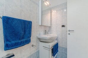 Ein Badezimmer mit einem weißen Waschbecken, einem Spiegel und einem blauen Handtuch.