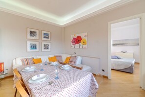 Ein Essbereich mit einem Tisch für vier Personen, einer Couch mit Kissen und einem Bett im Hintergrund.