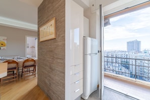 A modern kitchen with a refrigerator, wooden chairs, a dining table, and a large window with a city view. - GuestHost - Cozy apartment of 80 square meters, able to accommodate up to 4 people, located on the sixth floor of a building with a lift that can be opened with a key (supplied).The property boasts a panoramic balcony of 7 sqm with awning and a sea view  (Genova)