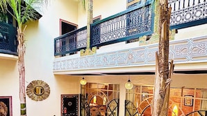 Un pati amb piscina, palmeres i zona de seients amb coixins de colors.