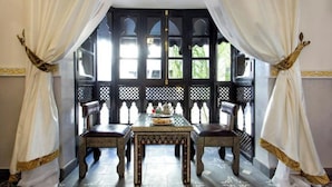 A room with a table and two chairs, a window with a lattice design, and a patterned floor. - Riad Chamade - Exclusive for your group, up to 12 pers, Medina Marrakech (Marrakech)