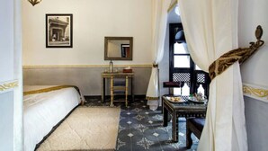 A room with a bed, a small table with a mirror, a sink, and a window with curtains. - Riad Chamade - Exclusive for your group, up to 12 pers, Medina Marrakech (Marrakech)