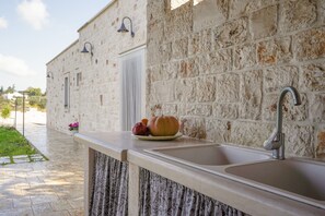 Una cocina con pared de piedra, un lavabo y un frutero.