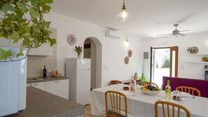 Een moderne keuken met witte kasten, een eettafel met stoelen en een plafondventilator.