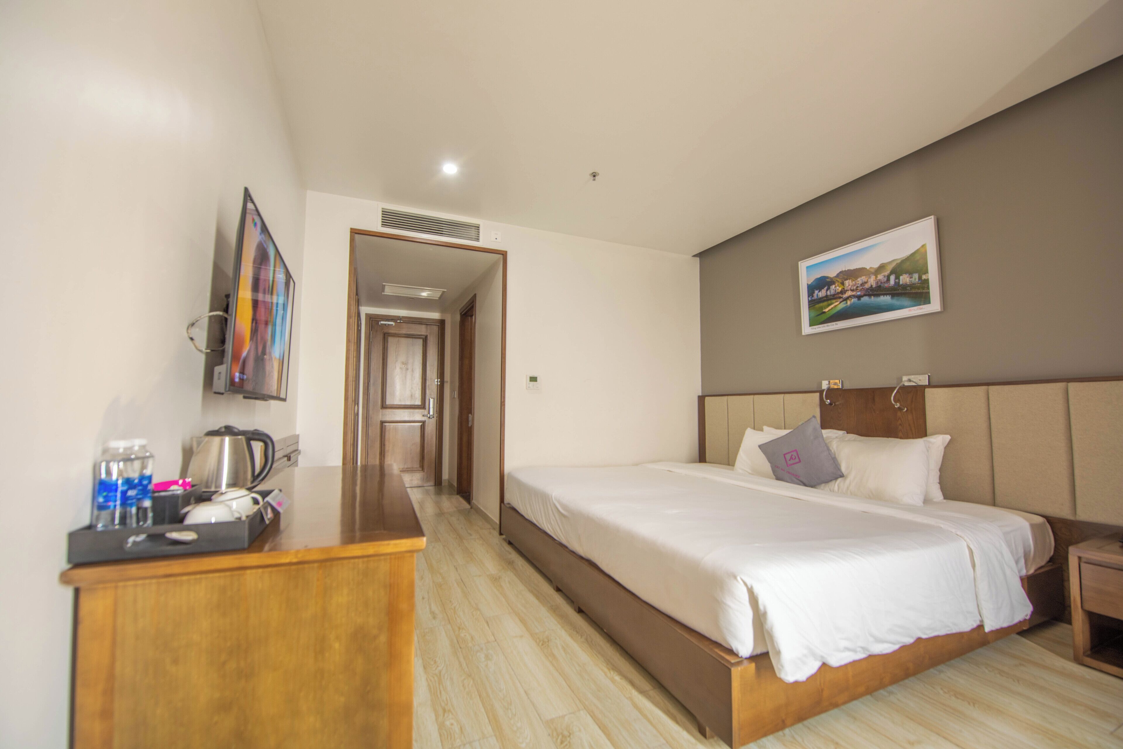 Una habitación de hotel con cama, escritorio con hervidor, cafetera y un cuadro en la pared.