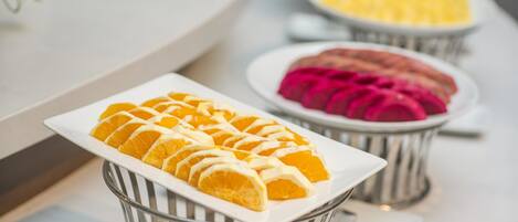 A buffet with neatly arranged fruit slices in metal baskets.