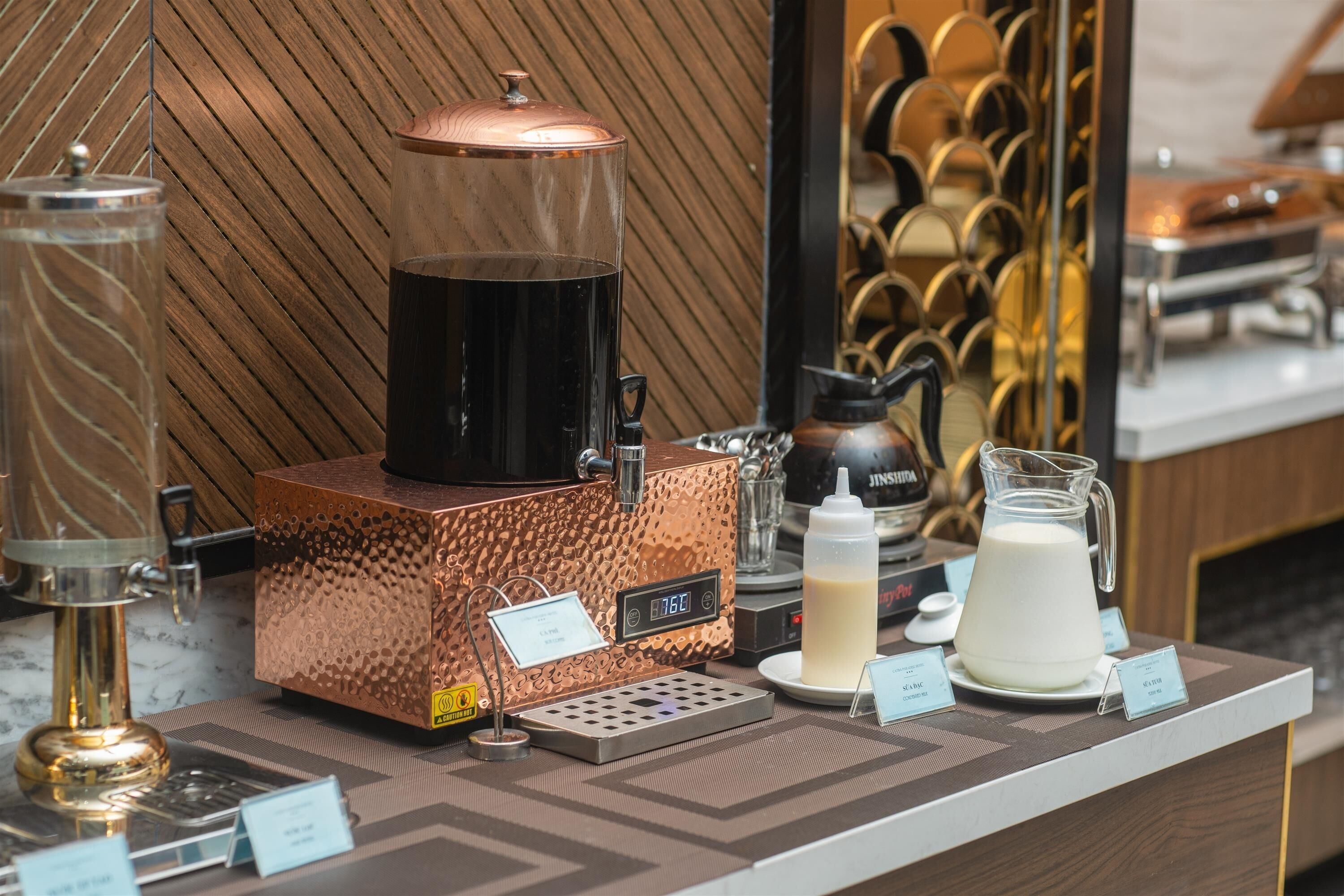 A coffee station with a coffee machine, milk jug, and a scale.