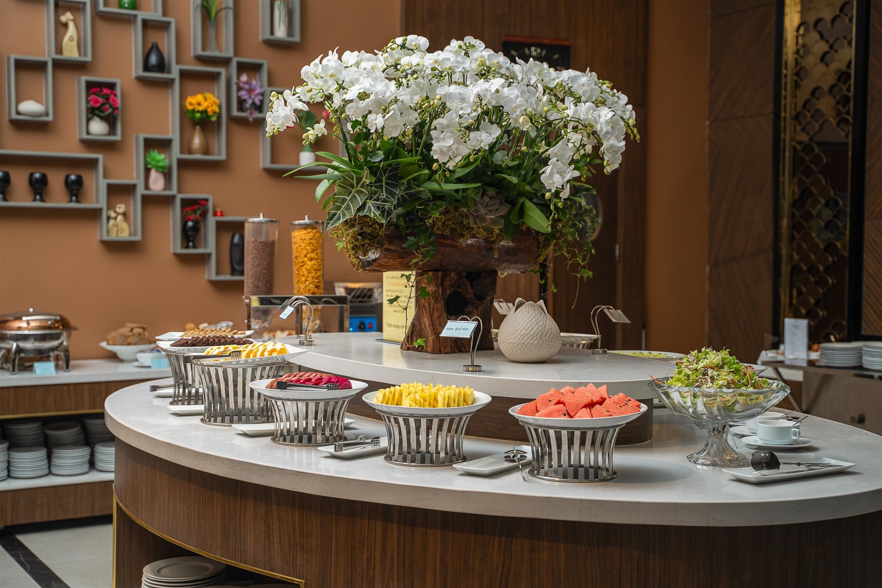 Montaje de bufé con diversas opciones de comida y un gran centro de mesa floral.
