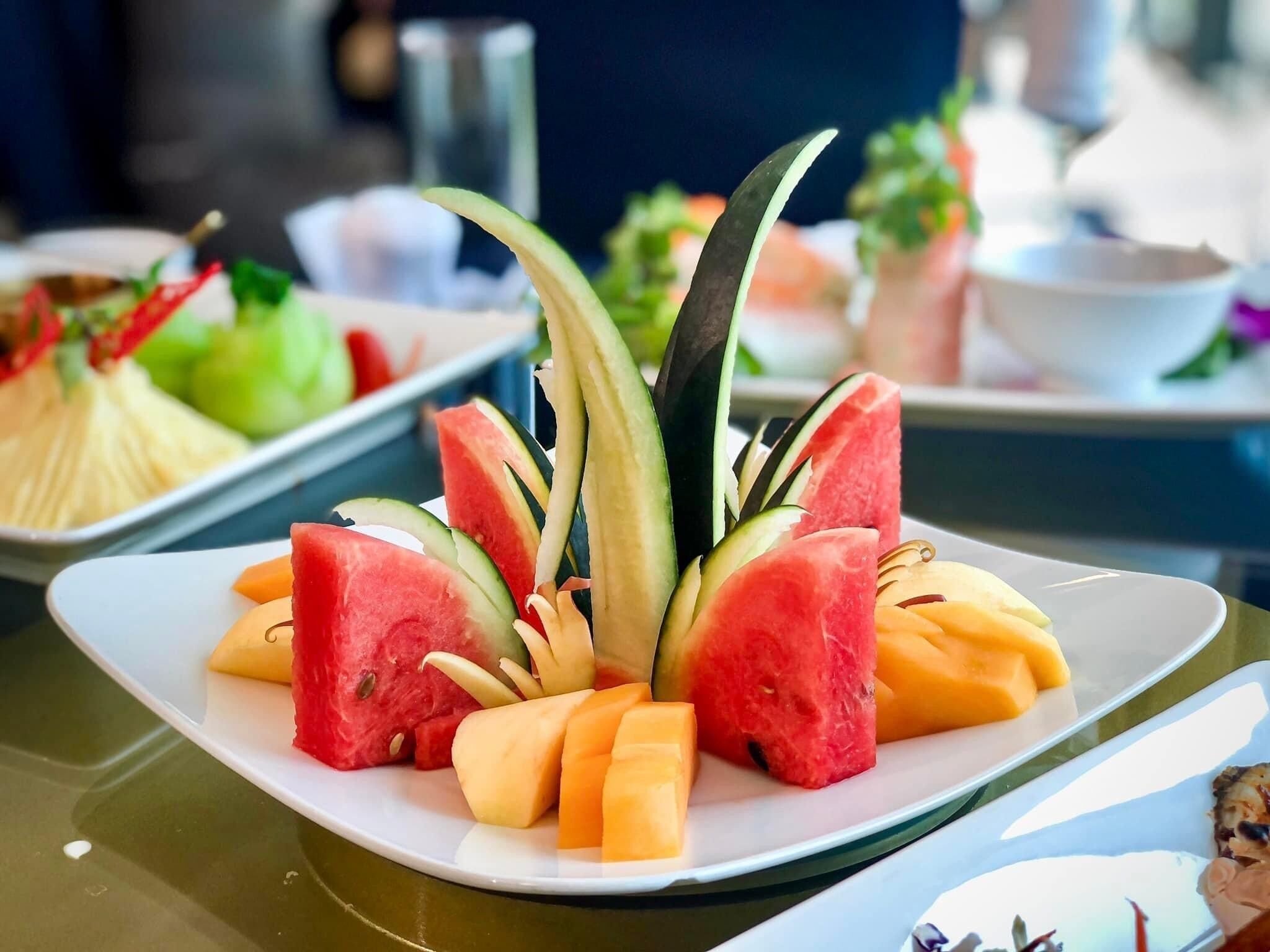 A plate of watermelon, cantaloupe, and cucumber arranged on a table.
