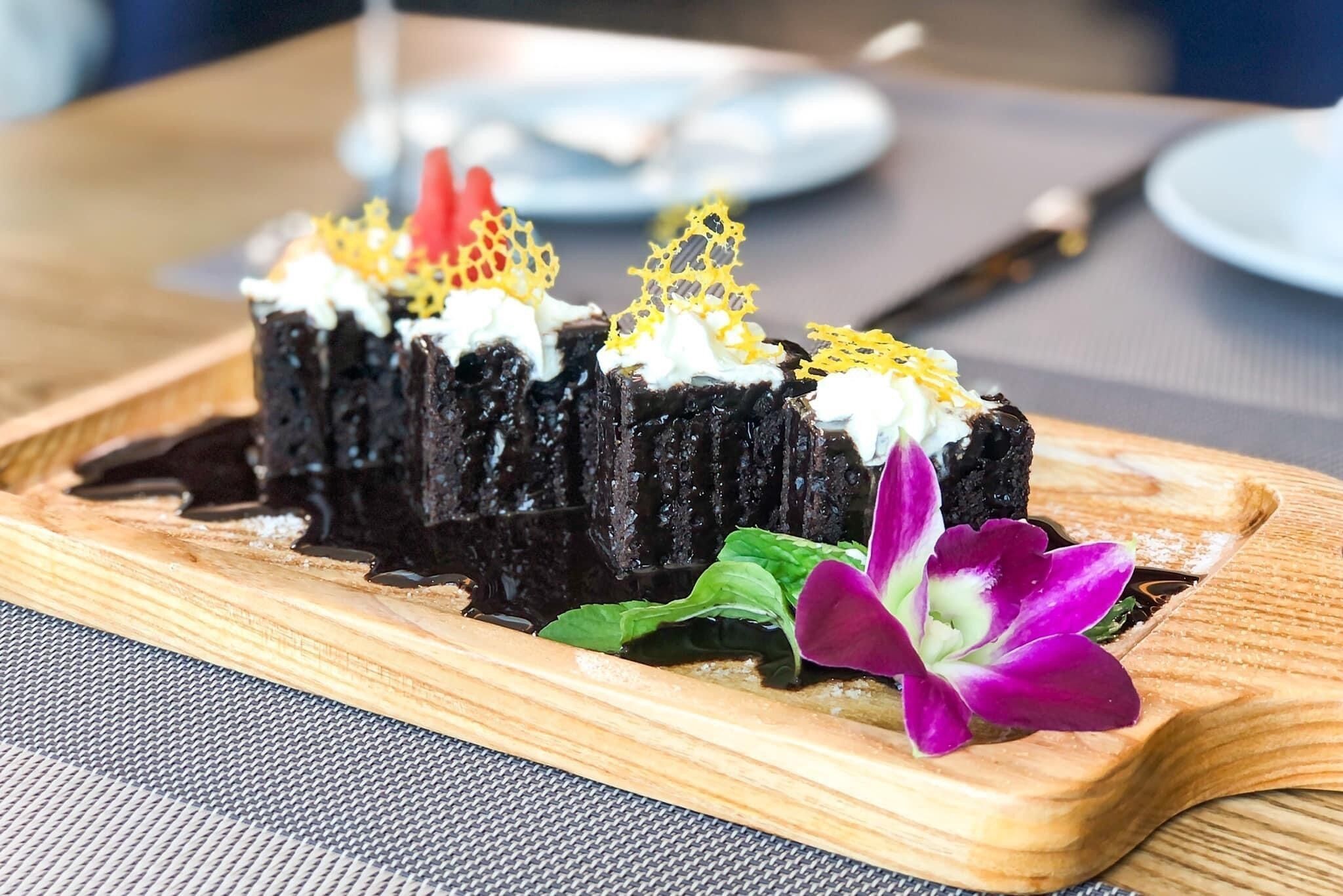 Un postre sobre una tabla de madera, con un cuchillo y un plato al fondo.