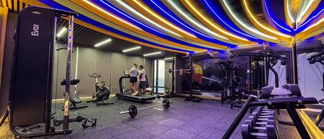 A gym with treadmills, weight machines, and a mirrored wall.