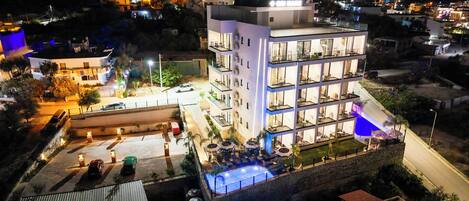 A multi-story hotel with outdoor seating and a swimming pool.